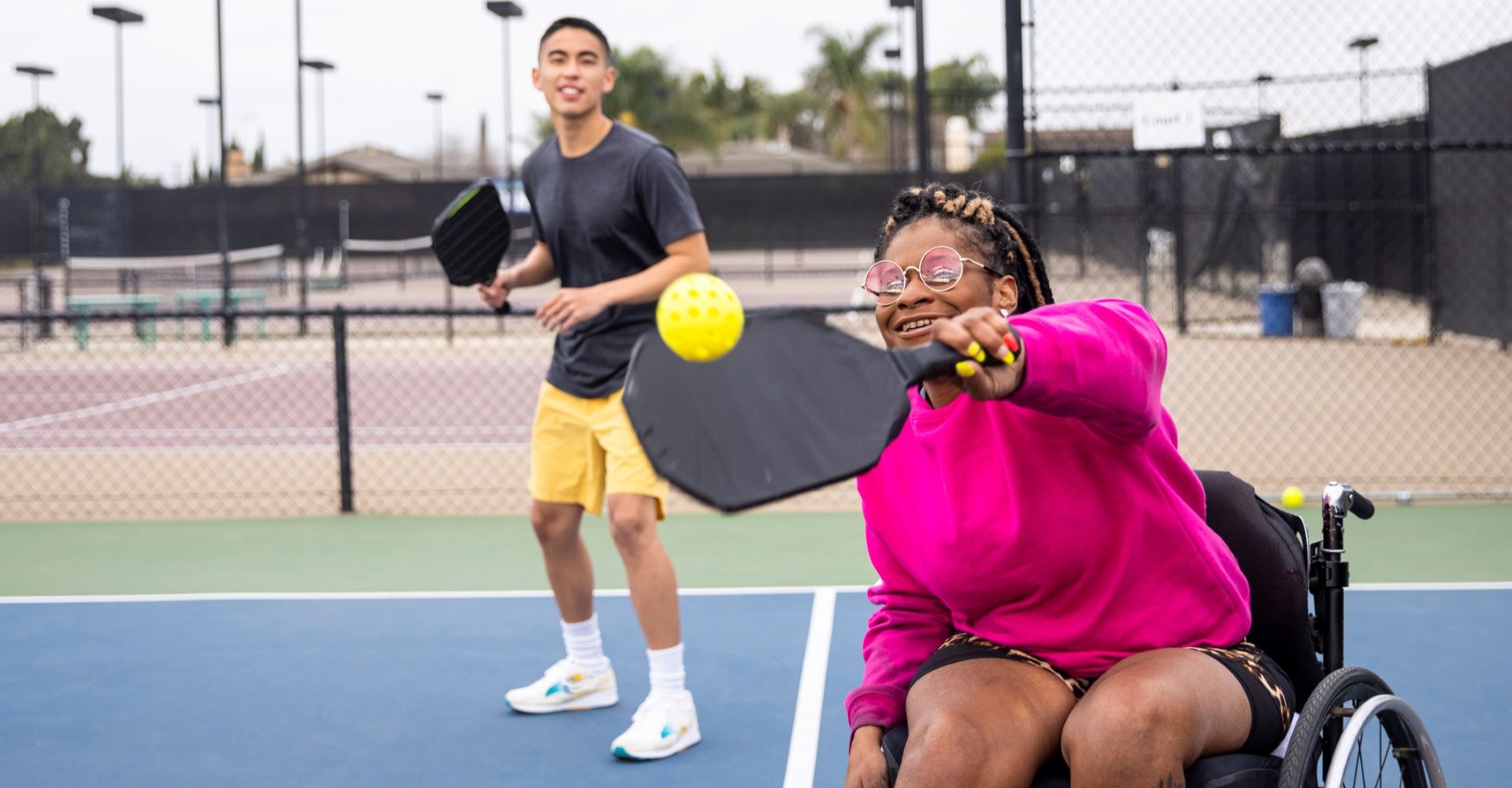 Outdoors Pickleball Court with man and disabled woman.