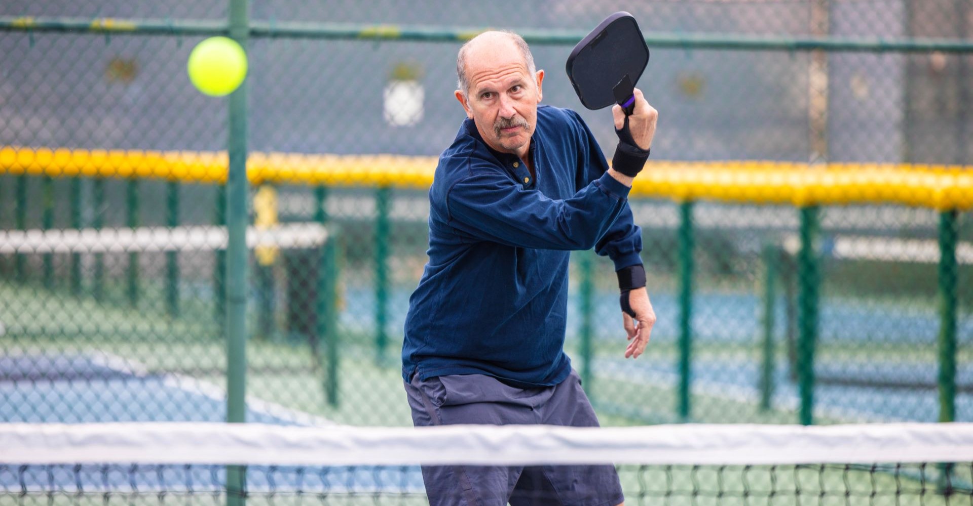 Outdoors Pickleball Court with senior man.