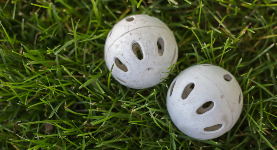 Wiffleballs laying on grass.